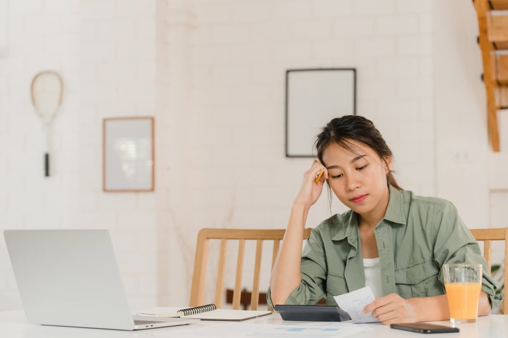 Relaxed woman working with documents and a laptop at home office desk.