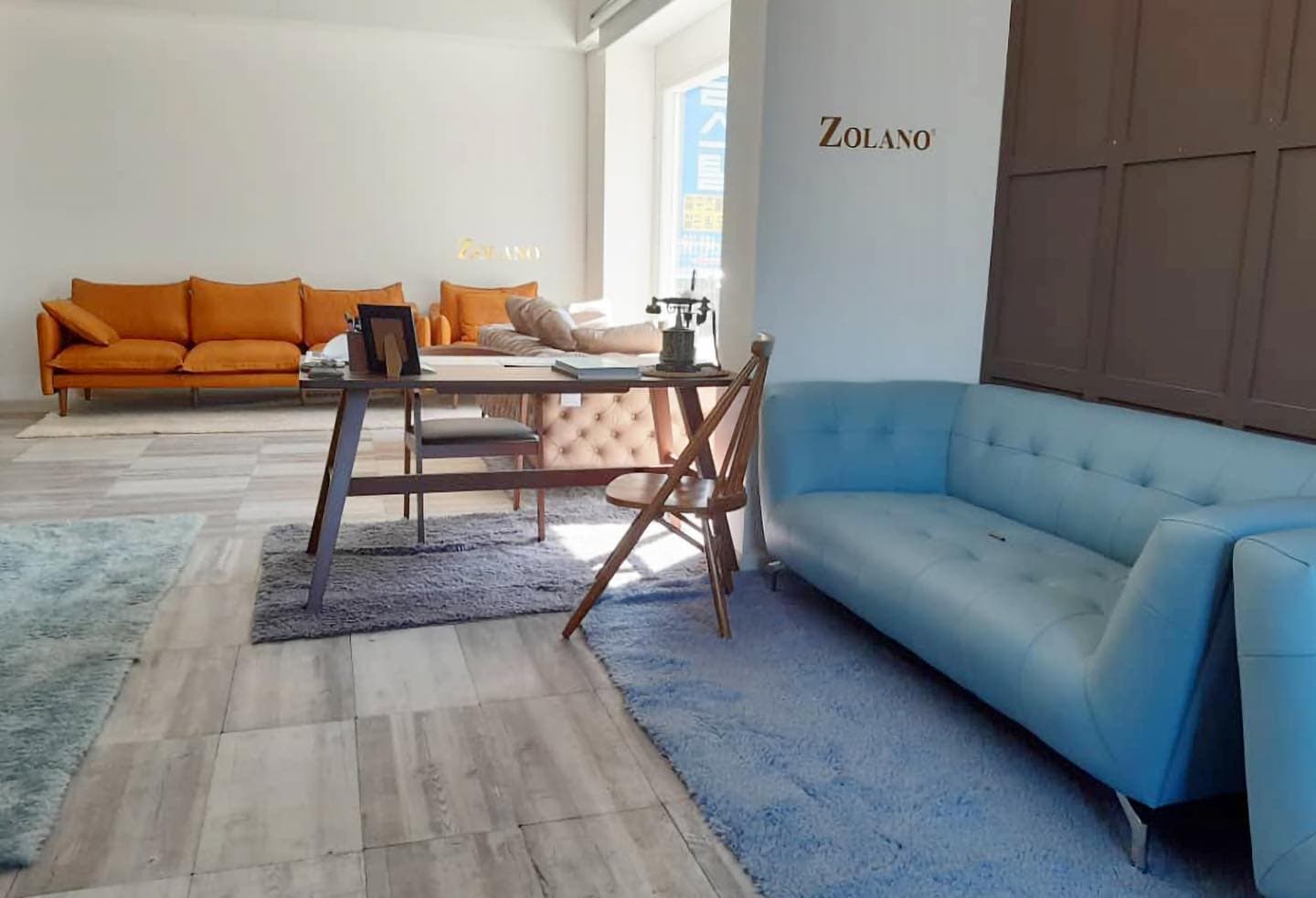 A colourful showroom interior with modern sofas and a desk at Zolano's first showroom in Korea (2020.