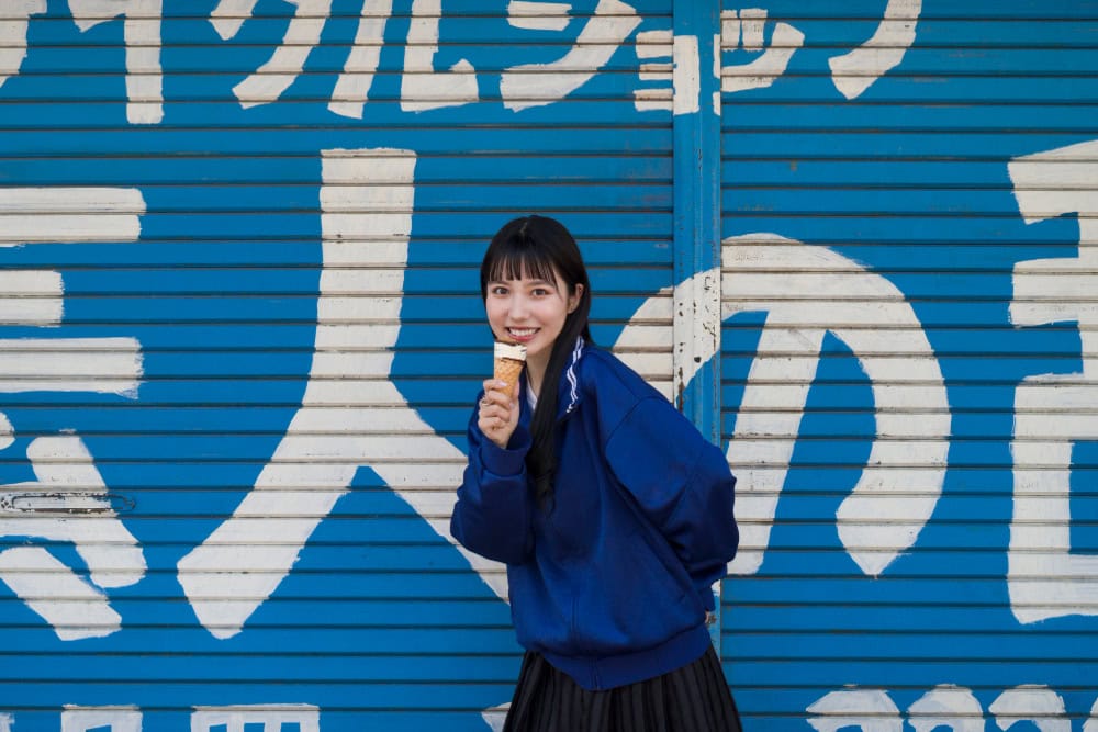 Enjoying ice cream in front of a blue graffiti wall in Japan.