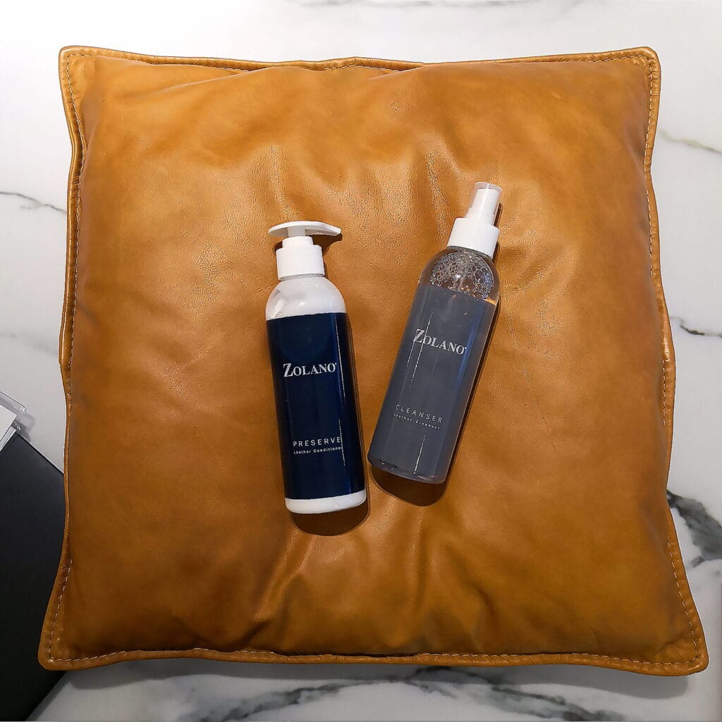 Zolano skincare bottles on a brown leather pillow, minimalistic skincare products display.