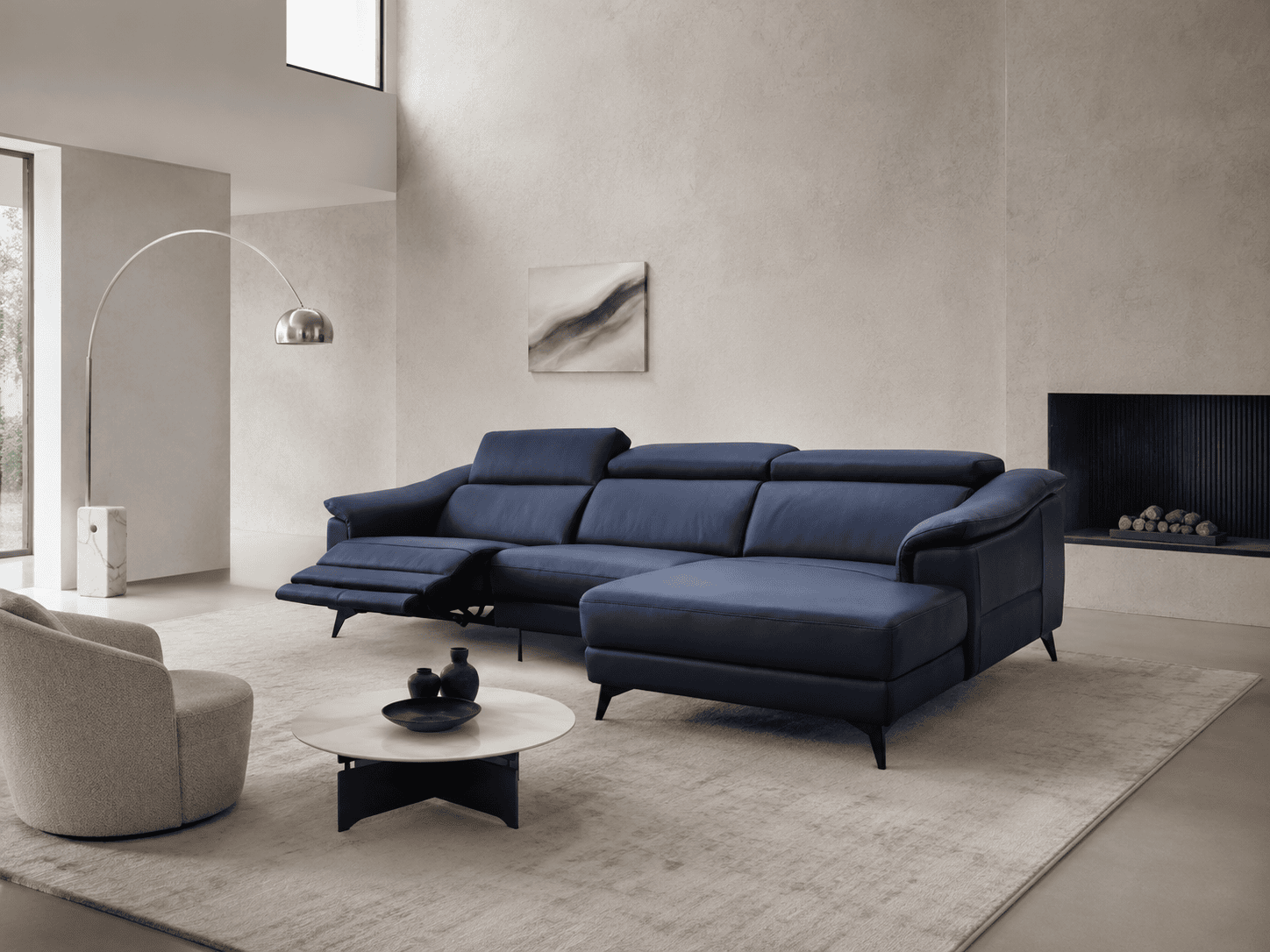 Modern navy blue sectional sofa in a minimalist living room with fireplace and artwork.