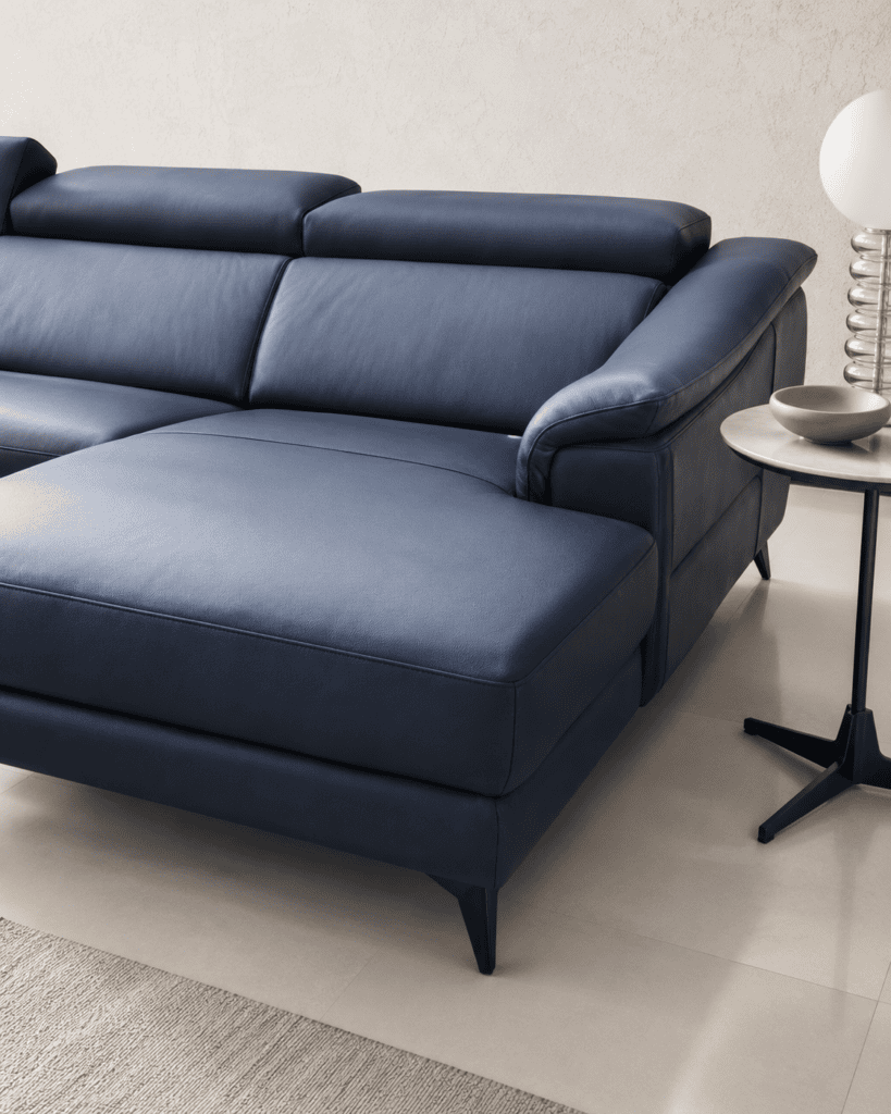 Modern blue leather sofa with black legs in a minimalist living room setting.