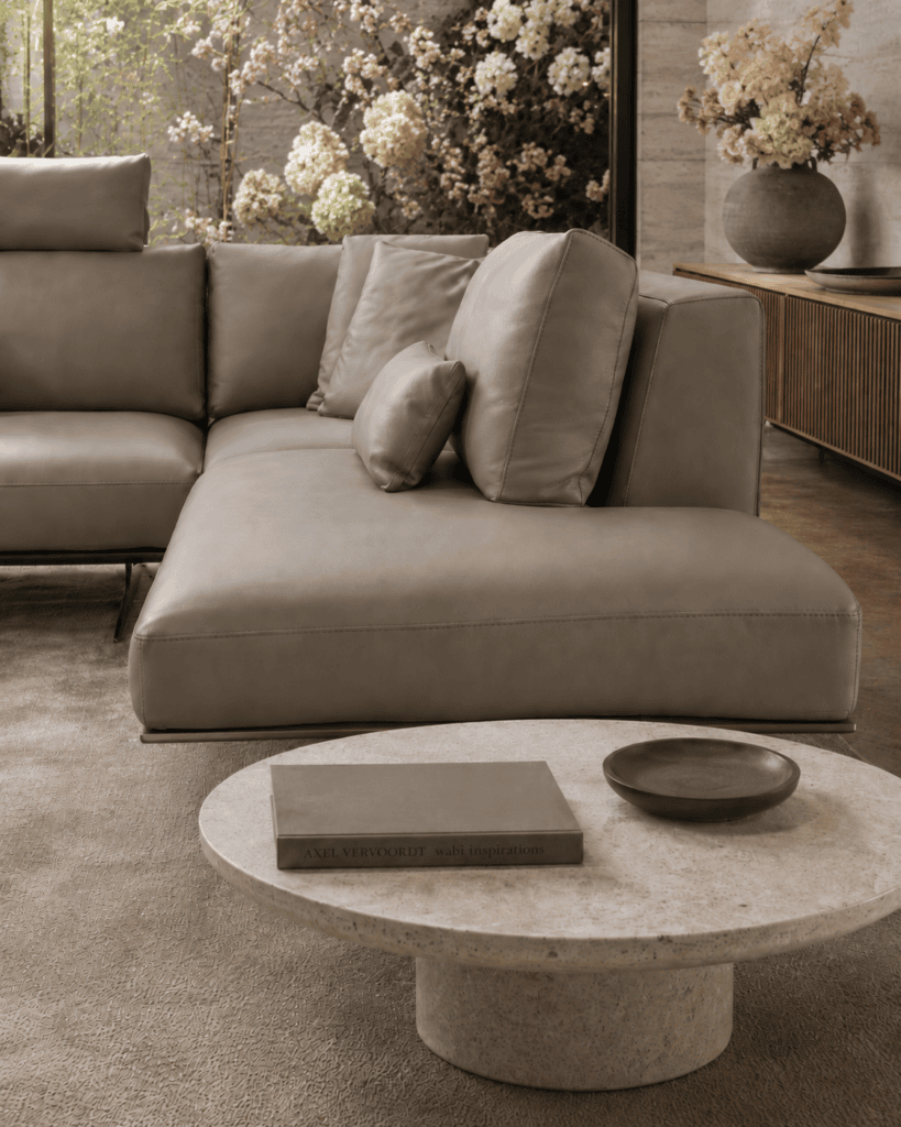 Modern grey leather sofa with cushions in a stylish living room with floral decor.