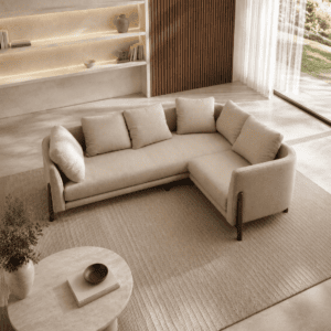 Modern beige sectional sofa in a bright living room with large window and wooden accents.