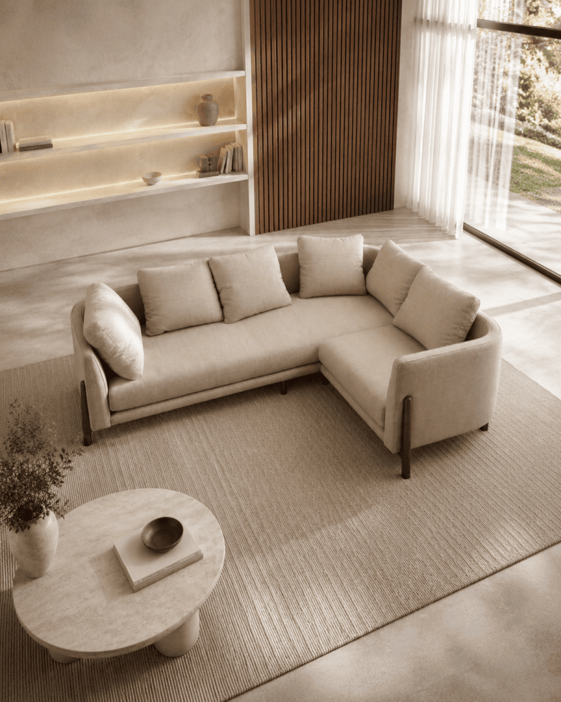 Modern beige sectional sofa in a bright living room with large window and wooden accents.