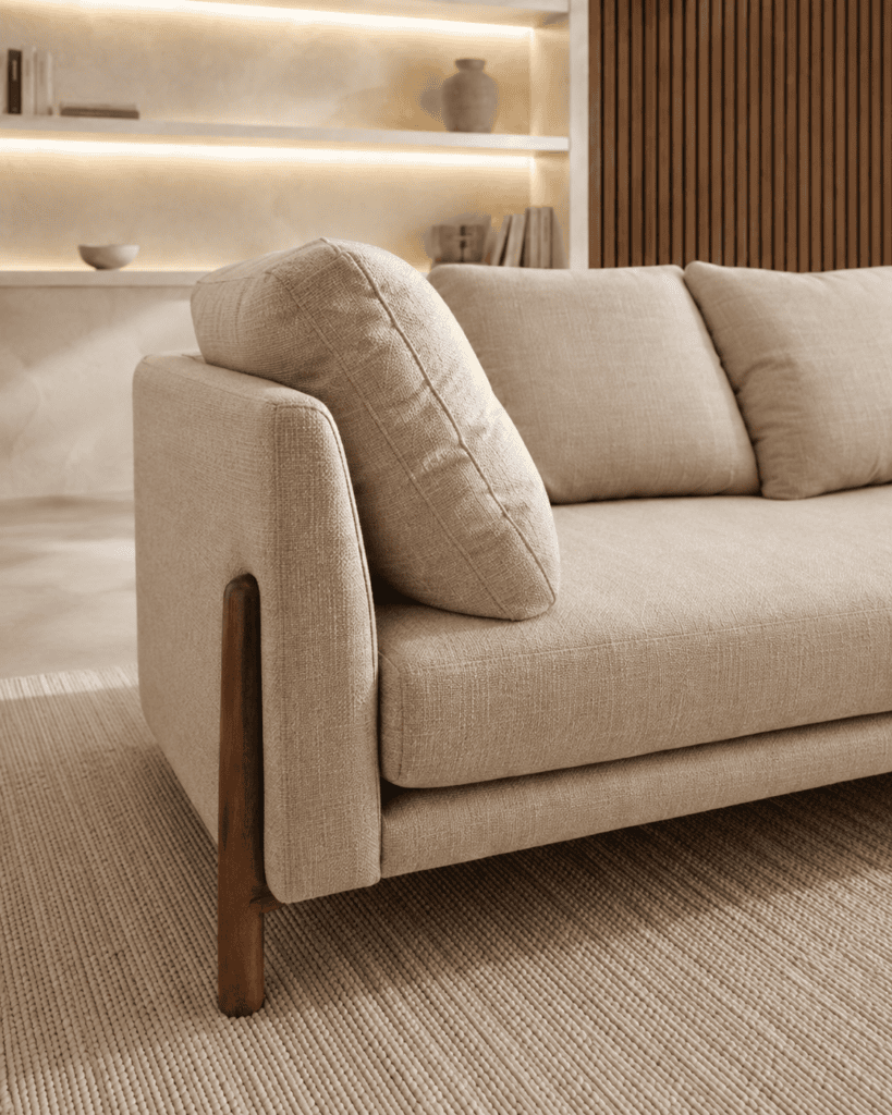 Modern beige sofa with wooden legs in a stylish living room setting.