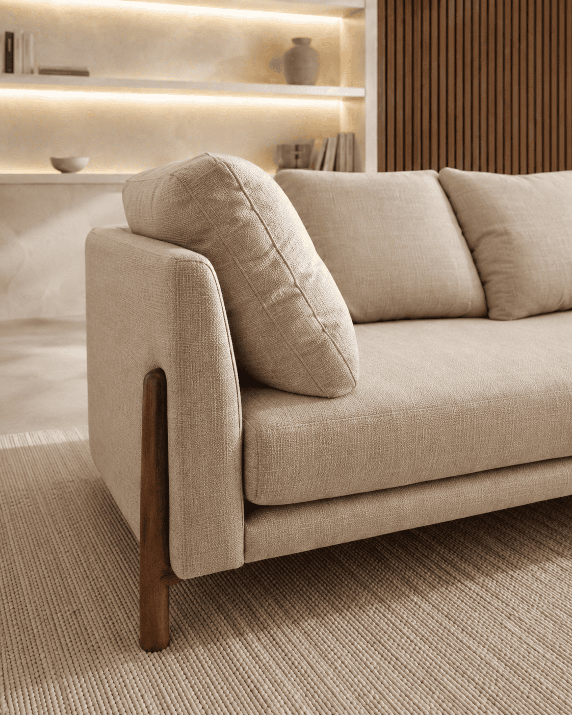 Modern beige sofa with wooden legs in a stylish living room setting.