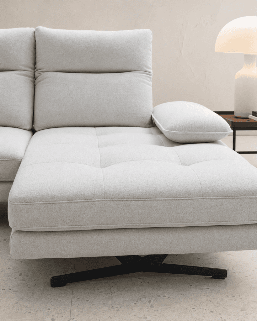 Modern light grey sofa with cushion and side table with lamp in living room.