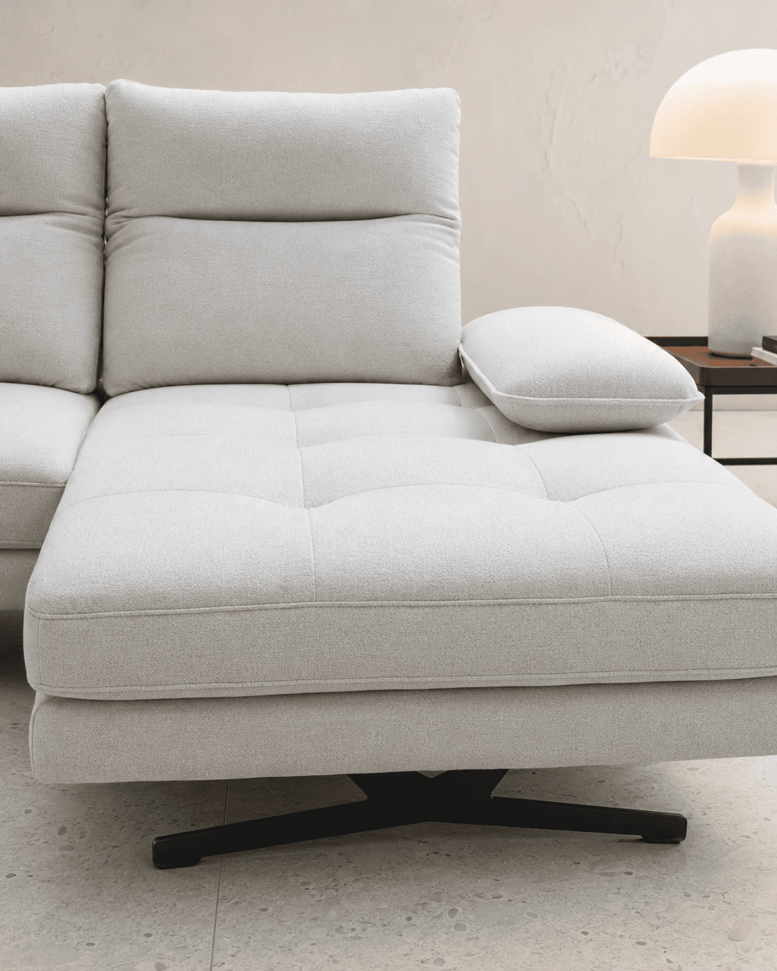 Modern light grey sofa with cushion and side table with lamp in living room.