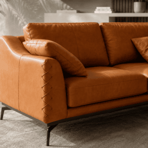 Elegant brown leather sofa with matching cushions in modern living room setting.
